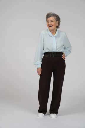 Vista frontal de una anciana sonriendo con una mano en la cadera