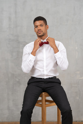 Man on a chair adjusting his bow tie