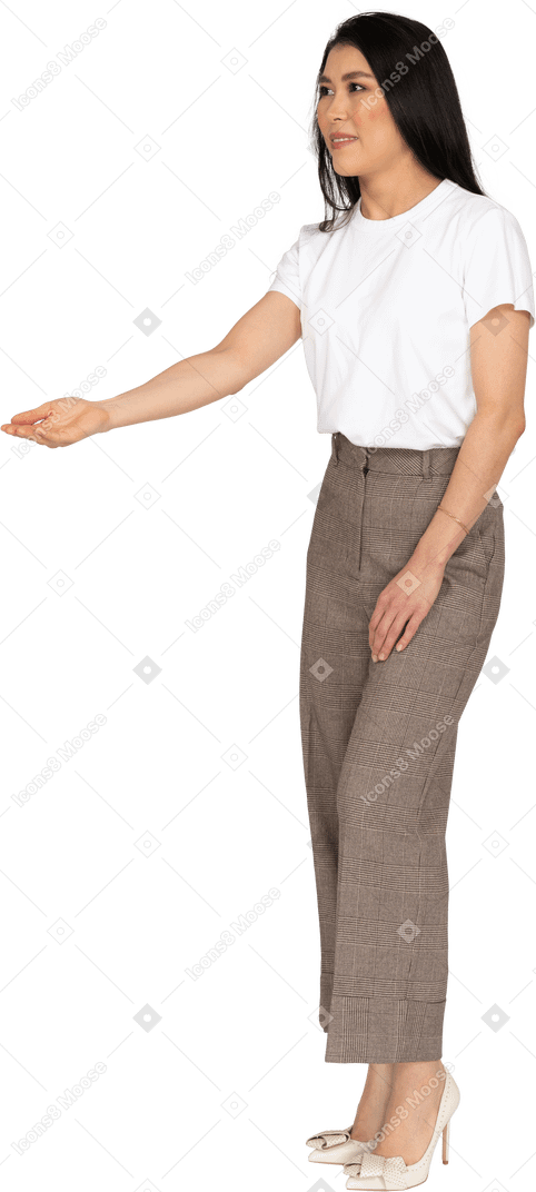 Vista di tre quarti di una giovane donna in calzoni e maglietta che tende la mano