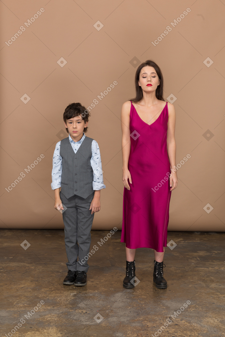 Femme en robe rouge, les yeux fermés, immobile avec un garçon