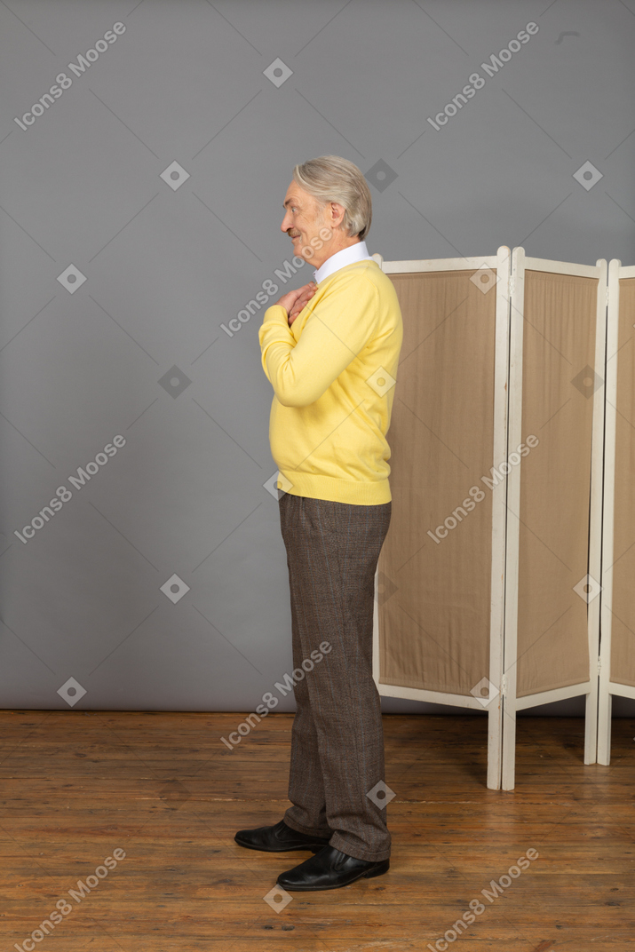 Vista laterale di un uomo anziano sorridente vicino allo schermo che attraversa le mani