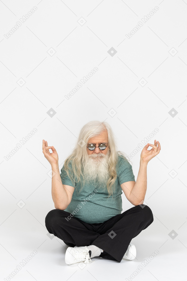 戴墨镜的老人坐着打坐的正面图