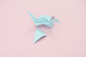 Blue origami crane with a torn off wing