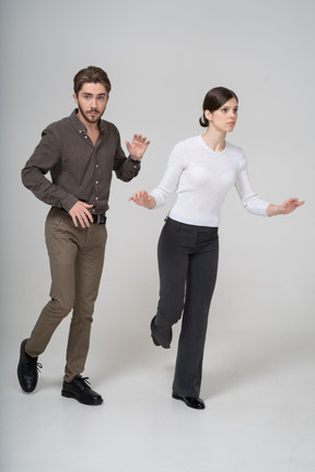 Vista de tres cuartos de una pareja joven en ropa de oficina levantando la pierna