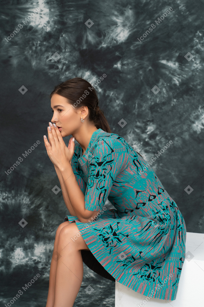 Side portrait of worried female in blue dress