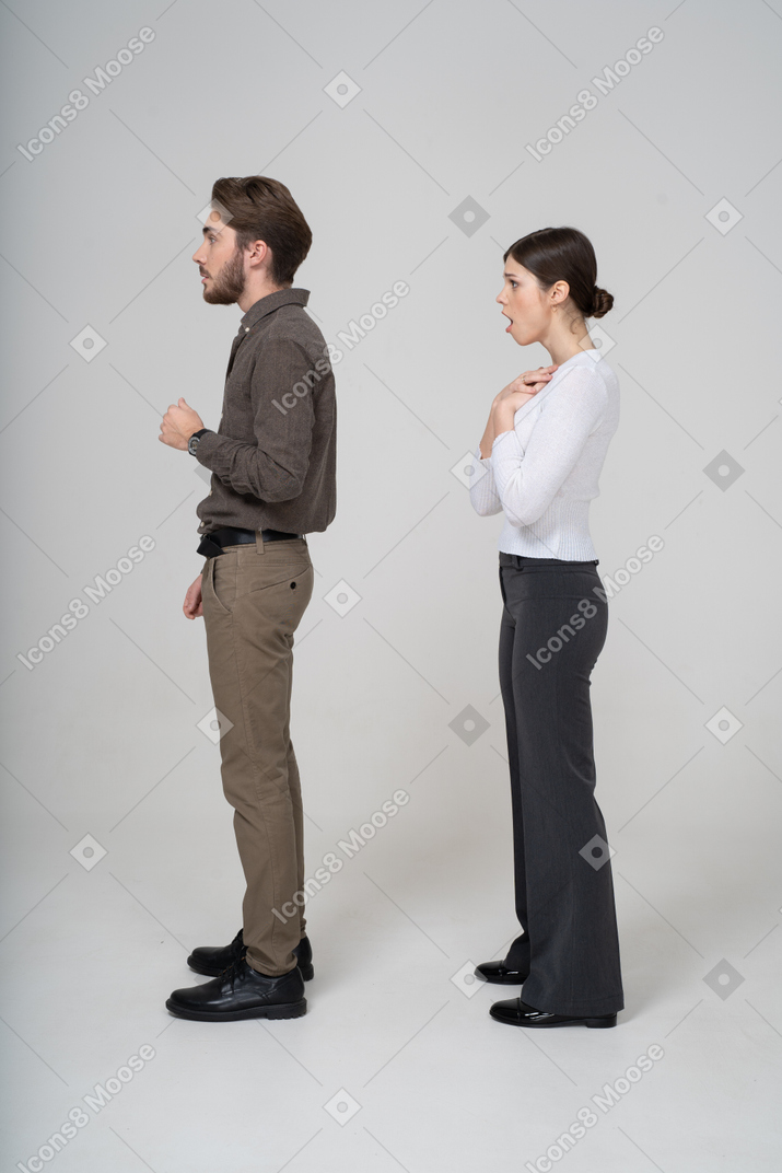 Side view of a shocked young couple in office clothing