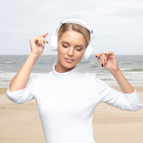 Woman enjoying music in headphones on the beach