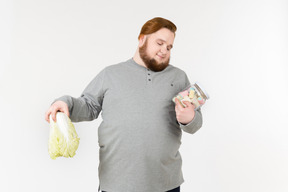 Bid bearded man choosing between cabbage and marshmallows