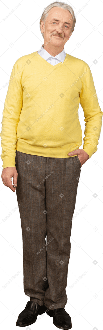 Vista frontal de um velho satisfeito em um pulôver amarelo colocando a mão no bolso e olhando para a câmera