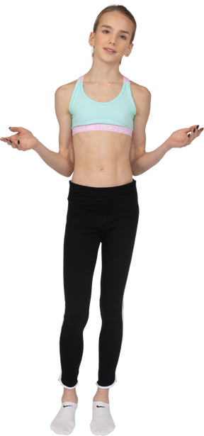 Vista frontal de una jovencita en ropa deportiva levantando las manos y mirando directamente