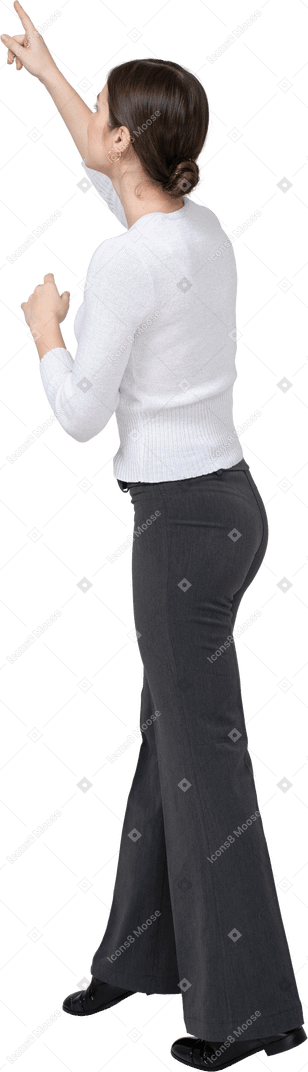 Vue latérale d'une femme en vêtements décontractés pointant vers le haut avec un doigt
