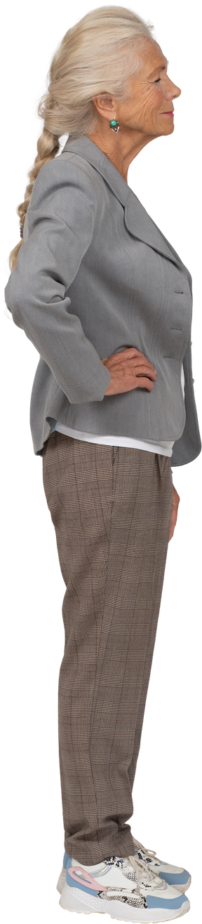 Vista lateral de una anciana en traje posando con las manos en las caderas
