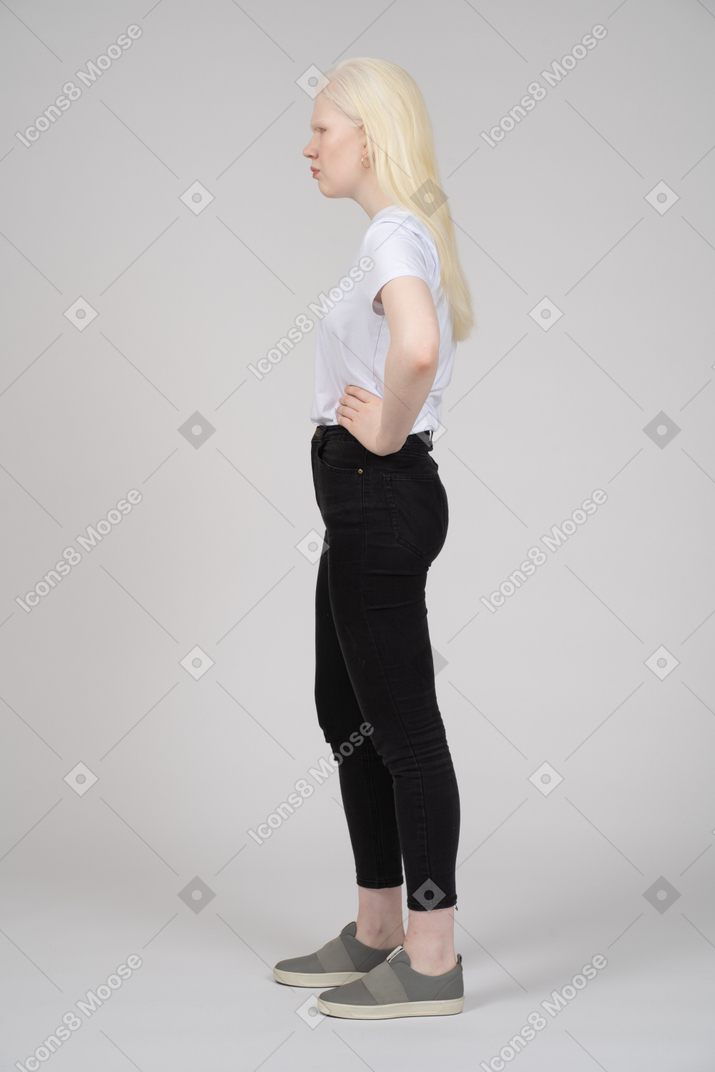 Side view of a frowning blonde girl with hands on her waist