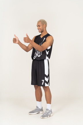 Vista de tres cuartos de un joven jugador de baloncesto masculino que muestra los pulgares para arriba