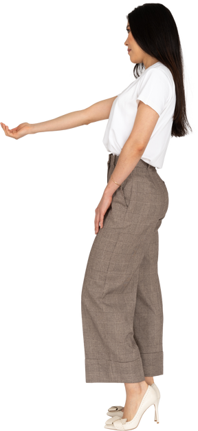 Vista lateral de una señorita en calzones y camiseta extendiendo su mano