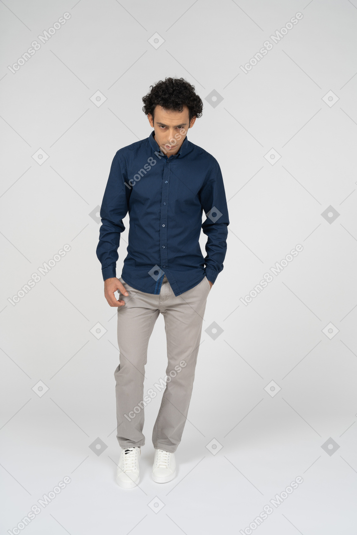 Vista frontal de un hombre en ropa casual posando con la mano en el bolsillo