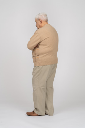 腕を組んで立っているカジュアルな服装の老人の側面図