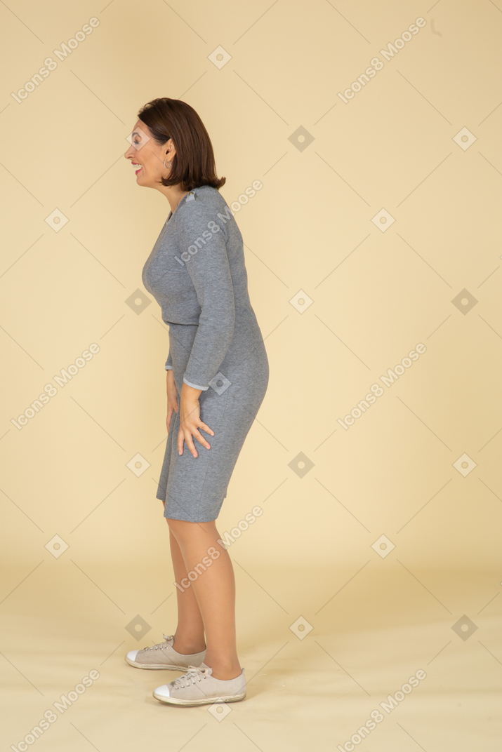 Vista lateral de uma mulher de vestido cinza