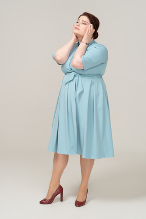 頭に触れる青いドレスの女性の正面図