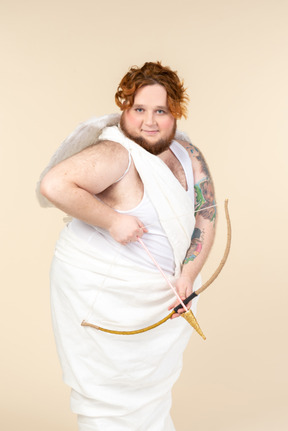 Young big man dressed as a cupid holding bow and arrow