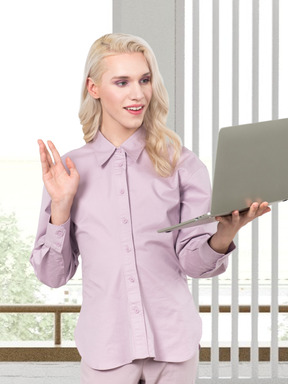 A woman looking at a laptop screen and waving