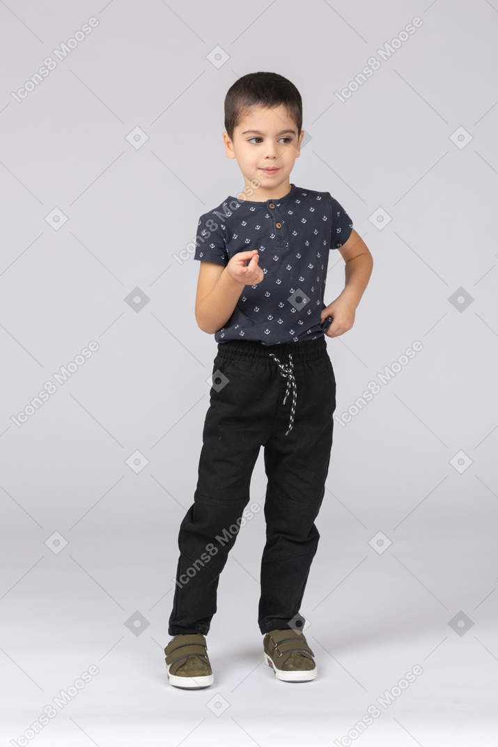 Vue de face d'un garçon mignon dans des vêtements décontractés pontant à la caméra avec le doigt