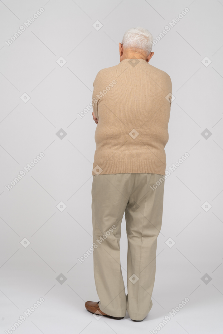 腕を組んで立っているカジュアルな服装の老人の背面図