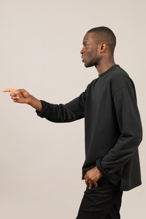 Side view of young man pointing with index finger
