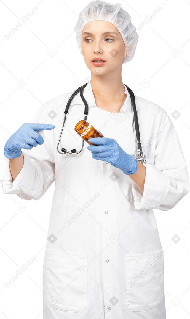 Front view of a young female doctor pointing finger at the jar of pills