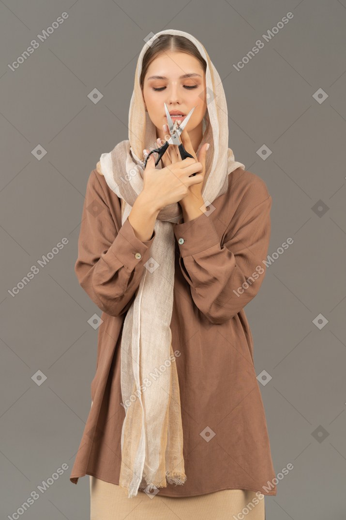 Woman in headscarf cutting a cigarette with scissors
