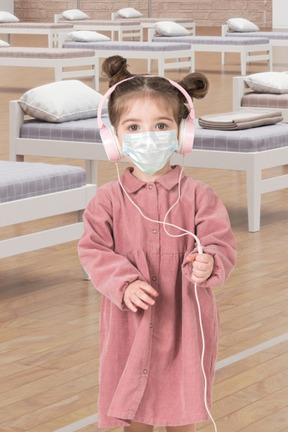 A little girl wearing headphones and a mask