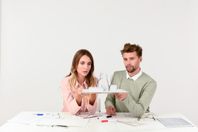 Female and male architects discussing the scale model of a house