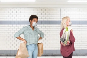 A woman with a face mask standing next to another woman