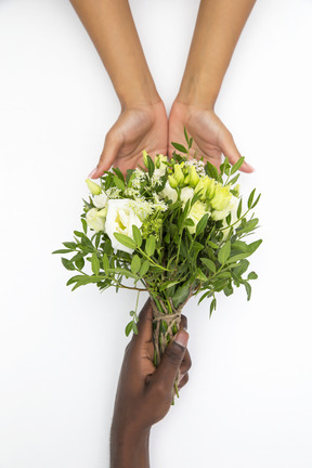 Schwarze männliche und weiße weibliche hand, die blumenblumenstrauß hält