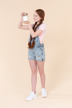 Teenage girl looking closely at jar she's holding