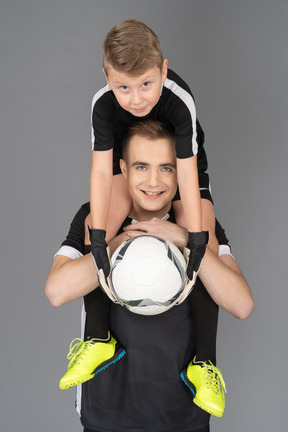 Close-up of a football player holding little boy on his neck