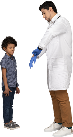 Médico calçando luvas cirúrgicas enquanto o menino olha