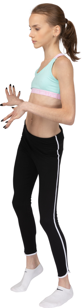 Вид в три четверти девушки-подростка в спортивной одежде, танцующей во время жестикуляции