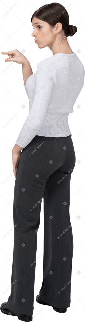 Vista posteriore di tre quarti di una giovane donna in abiti da ufficio che mostra le dimensioni di qualcosa