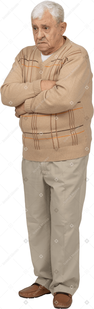 Vista frontal de un anciano triste con ropa informal de pie con los brazos cruzados