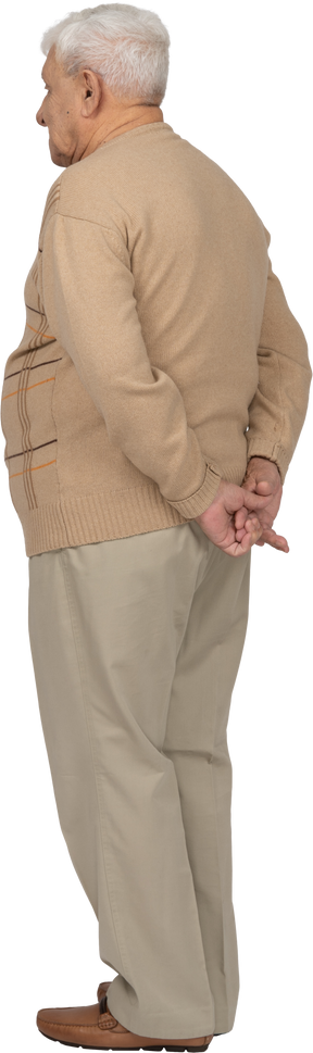 Rear view of an old man in casual clothes standing with hands behind back