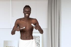 Homem seminu segurando pasta de dentes e escova de dentes