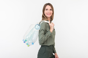 Giovane donna in possesso di un sacchetto di spago con bottiglie di plastica