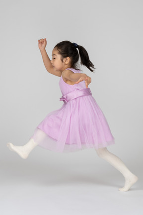 Girl in a pink dress making a big step forward