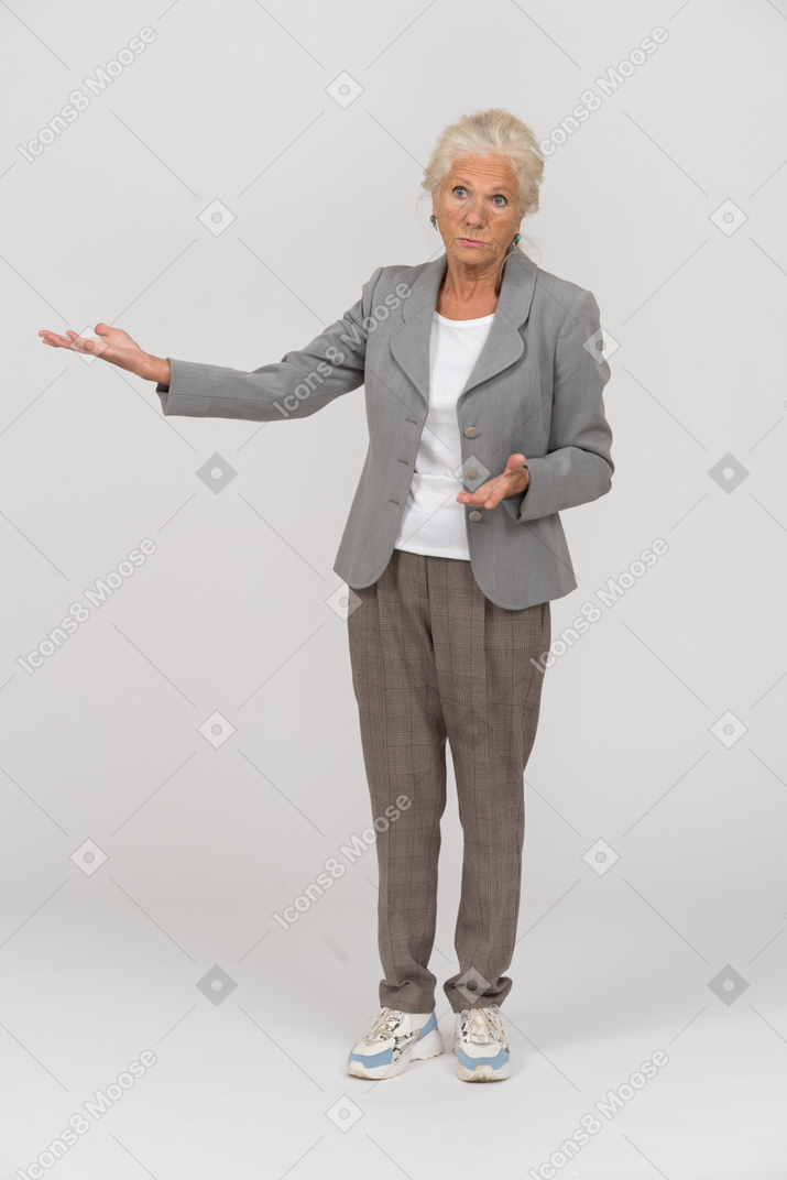 Front view of an old lady in suit pointing with hand