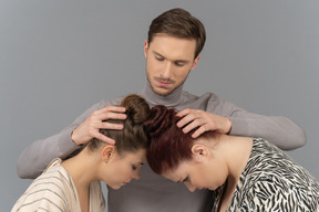 Young man touching two women's napes of the necks