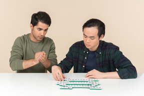 Amigos interraciais sentado à mesa e jogar o jogo de tabuleiro