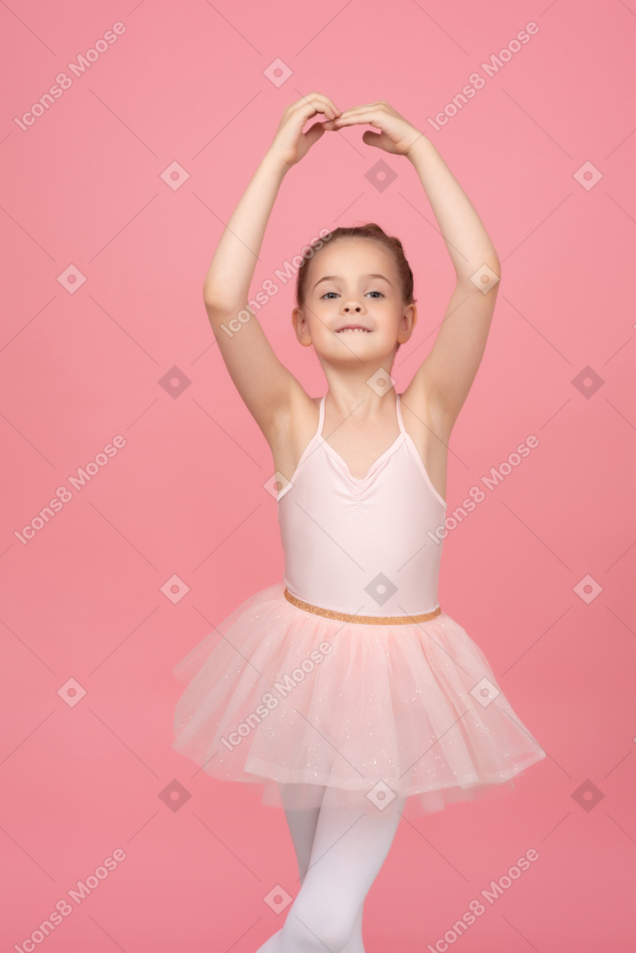 Bambina che indossa un tutù e in piedi in posizione di balletto
