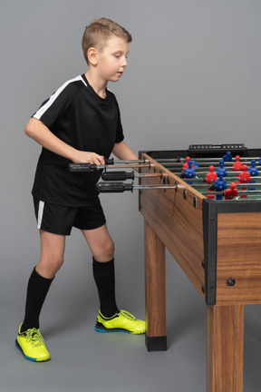 Side view of a boy playing foosball