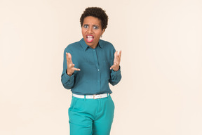 Mujer negra con un corte de pelo corto, vestida de azul, de pie contra un fondo pastel liso, con aspecto emocional